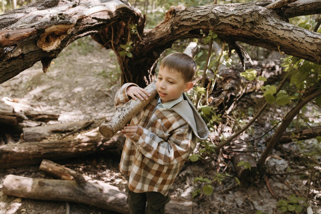 Enfant portant une branche pour jouer en forêt