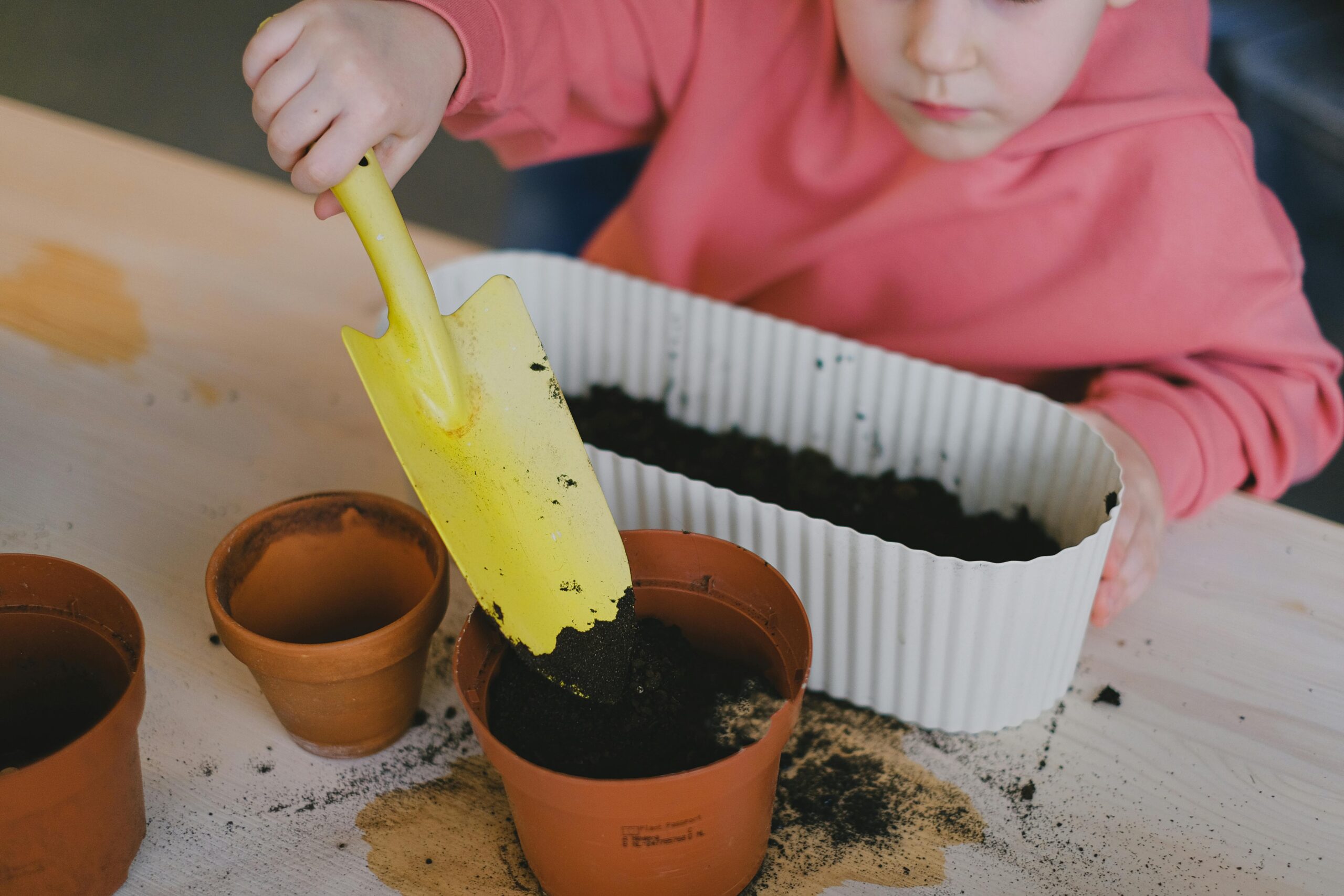 Enfant mettant de la terre en pot pour son potager